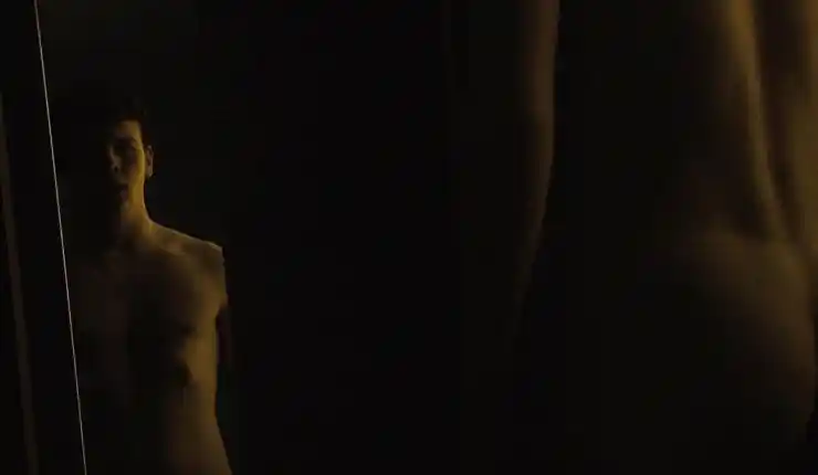 A man stands in front of a mirror in dark room in Scottish based horror Outcast.