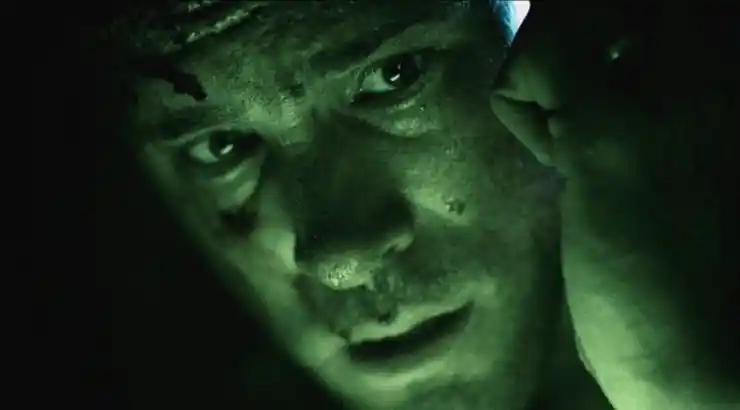 a man lit up in green looks worried in Buried