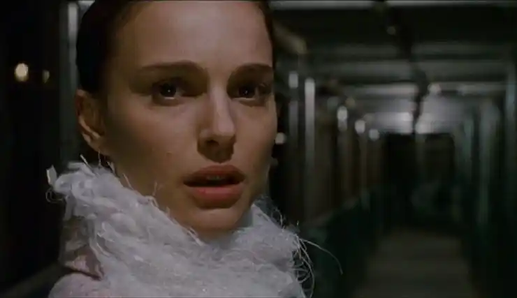 A young woman in white looks a little spooked in a hallway (Black Swan, 2010)