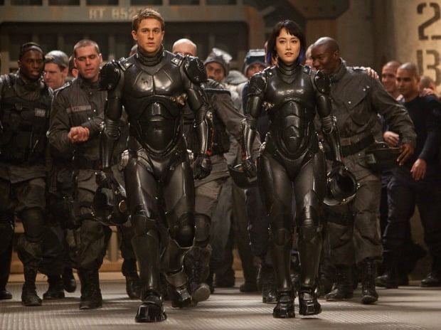 A group of people in strange suits walk towards the Jaegers in Pacific Rim