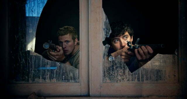 2 men with guns aimed out of a broken window