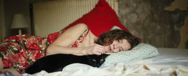 Isabelle Huppert lying on a bed in things to come
