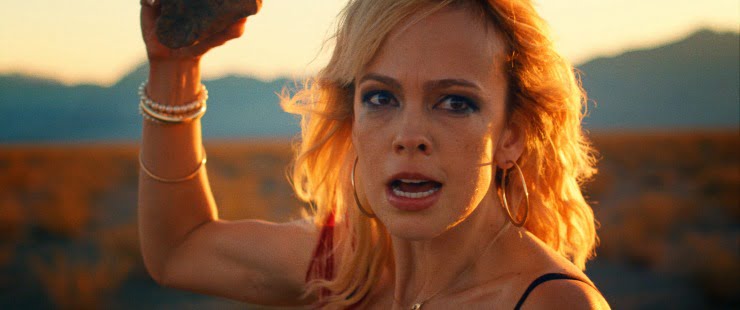 A woman (Brittany Allen) protects herself with a stone in It stains the sands red