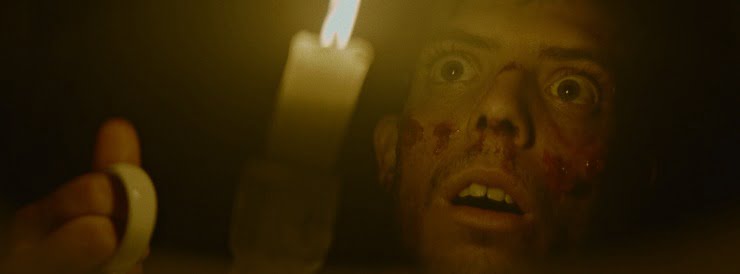 A shocked young man with a candle in the dark in The Night Of The Virgin