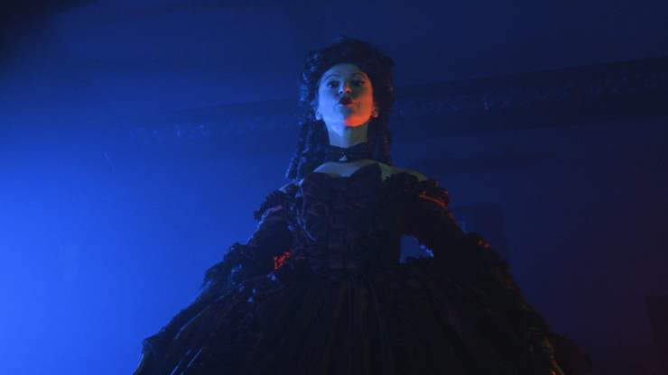 A woman in period dress on a blue background in Automata