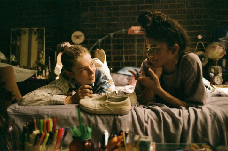2 girls lie on a bed together in Euphoria