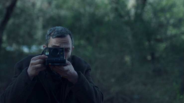 A man with a polaroid camera in Apples
