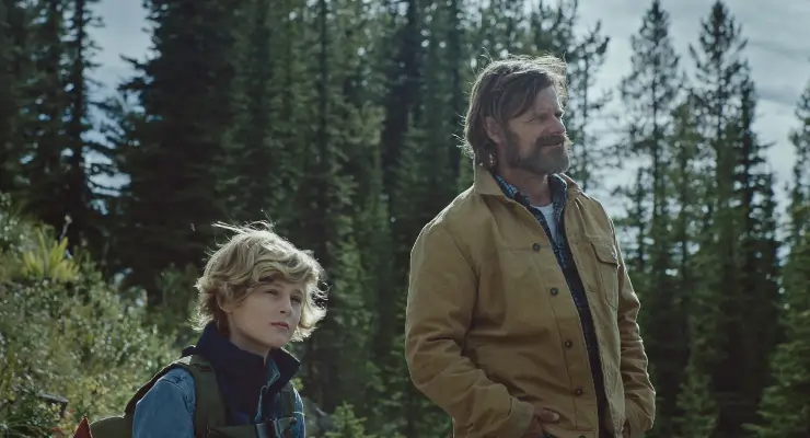 Boy stands with his father in Cowboys (actors sasha knight and steve zahn)
