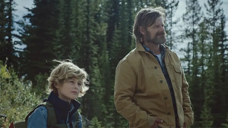 A man stands with his son in the forest in Cowboys