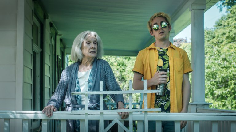 A young man stands on an balcony with an older woman in Jump Darling