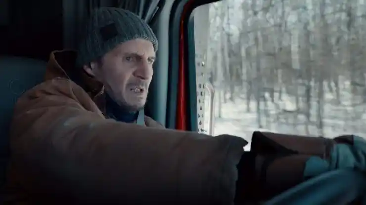 A man in a hat drives his truck in Ice Road