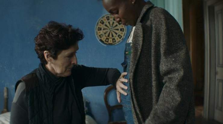 An older woman touches the stomach of a younger pregnant woman in Kindred.