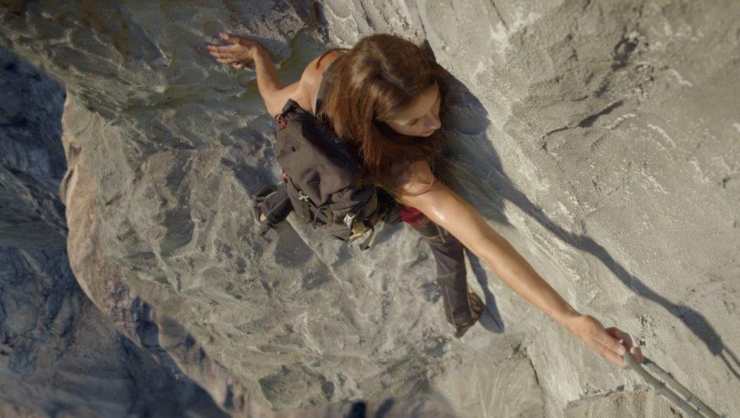 A woman attempts to climb a mountain hanging onto the edge