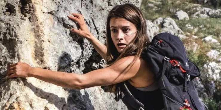 a woman hangs onto the rocks in fear