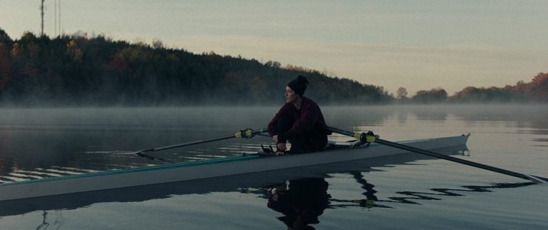 A young woman rows alone on waters in a boat