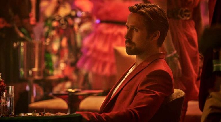 A bearded man sits in a red room in Netflix. The Gray Man
