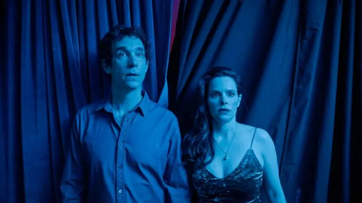 A worried man and woman stand in a blue tinted room in The End Of Sex.