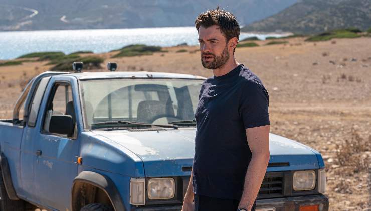 man looks concerned standing in front of old car