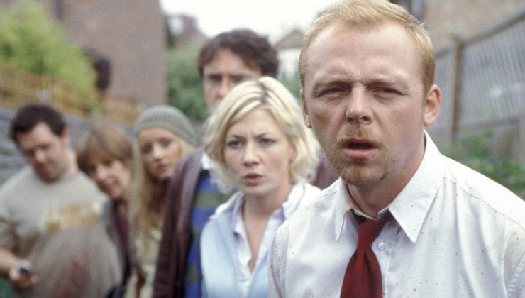 A group of people follow a man with red on his shirt
