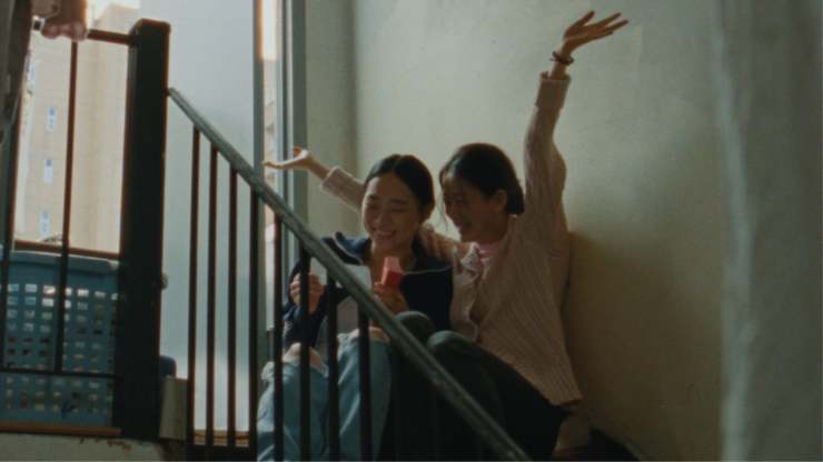 2 Asian women sitting on stairs with mobile