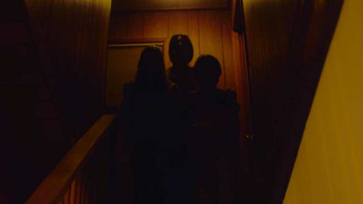 3 Dark figures stand at top of stairs