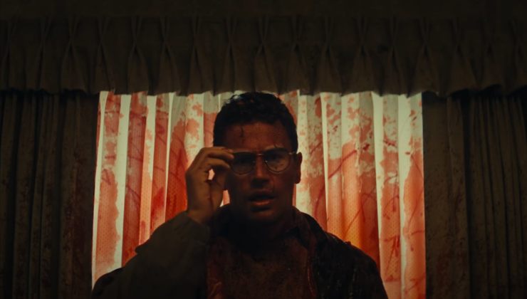 A blood soaked man fixes his glasses