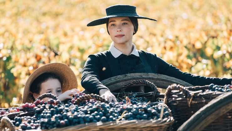 A woman with a young girl gathers grapes