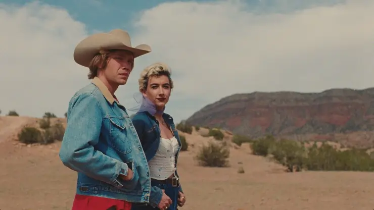 Young man in a cowboy hat stands with young trans woman in National Anthem
