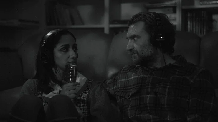A man and woman sit down with headphones for a podcast in Don't Die
