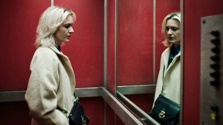 Woman looks at herself in Elevator mirror in Perla