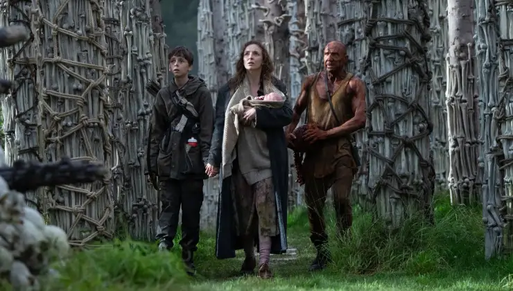 A scene of a man, young boy and woman with infant walking away from something in 28 Years Later