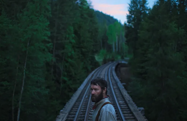 A man stands alone (Joel Edgerton) on a rail track in Train Dreams