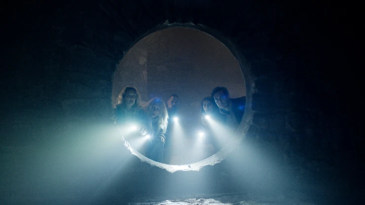 A group of people look down a hole to see if they find anything in Troll 2