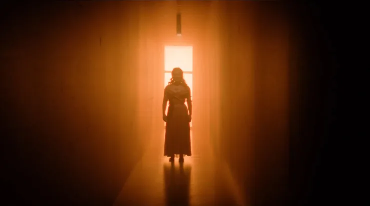 A female stands in a illuminated corridor in what she doesn't know