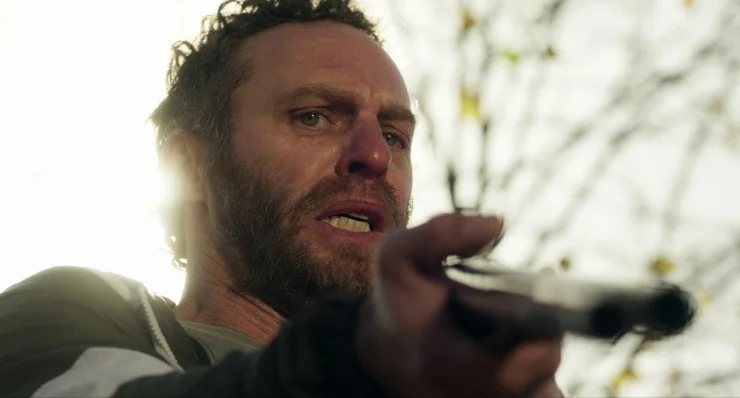 A man in When Evil Lurks aims a gun at someone