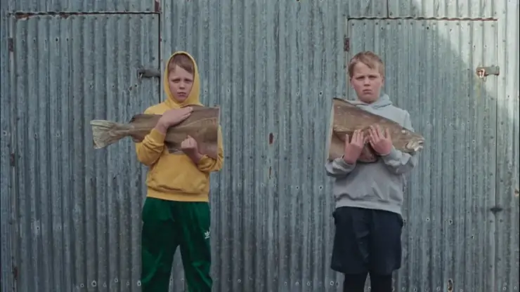 2 boys hold 2 parts of a fish in The love that remains