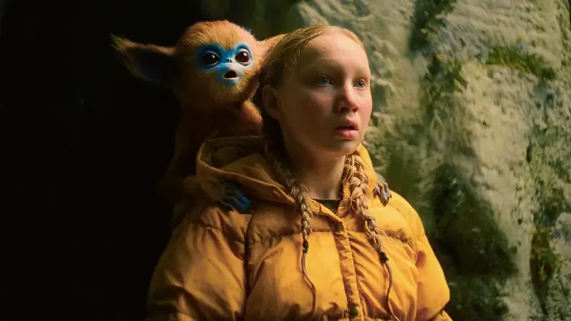Yuri (Helena Zengel) staring in the distance with the Baby Ochi on her shoulder in The Legend of Ochi