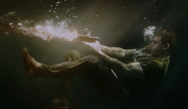 A man fires a gun underwater in The Drowned