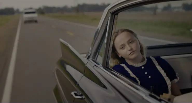 A young girl sites in back of a car unaware a white van is tracking the car in the man in the white van