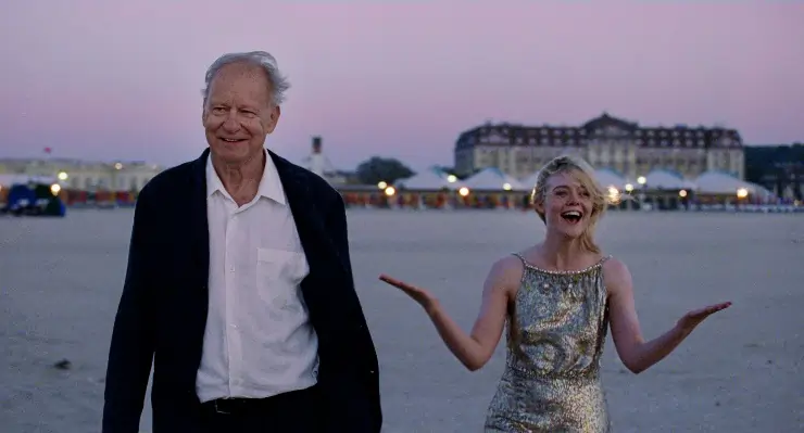 An older man and younger woman enjoy a stroll along a marina or seafront