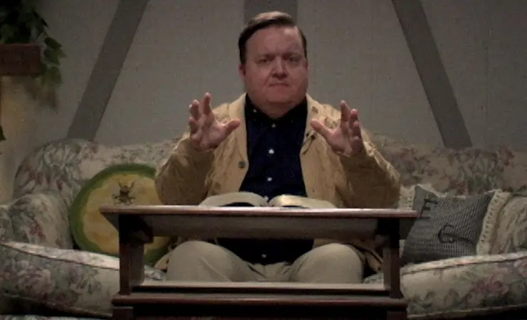 An old man preaches sitting down in Man Finds Tape.