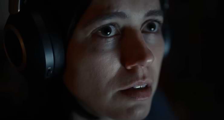A woman with headphones looks on in the dark in Undertone.