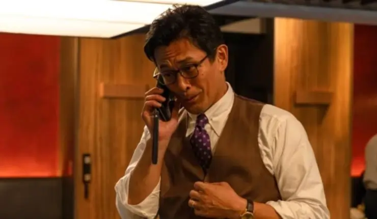 A well dressed Japanese man chatting to someone on the telephone
