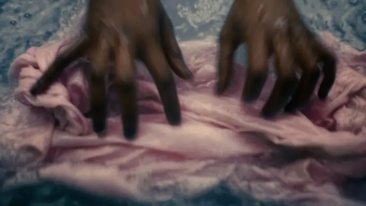 A pair hands fix a piece of material in First Days