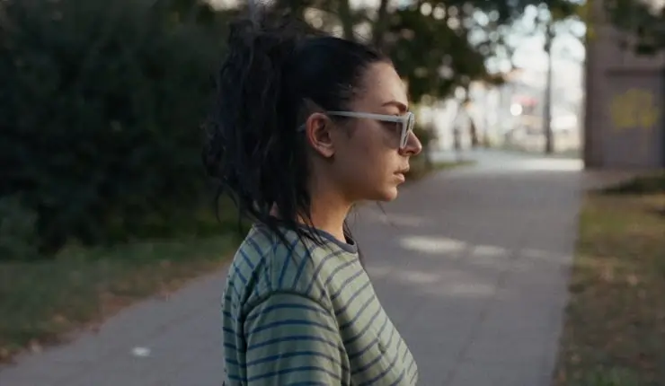 A dark haired woman in sunglasses looks shocked