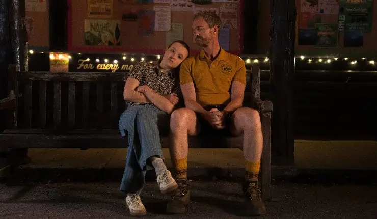 a young woman leans her head into a man on a bench in Sunny Days