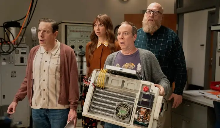 A man stands with his friends holding a machine can he fix it?