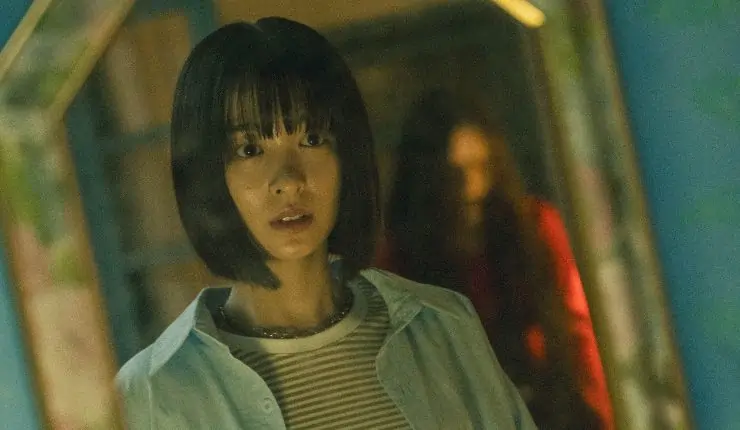 A Japanese woman reluctantly looks into the mirror and sees something standing behind her.