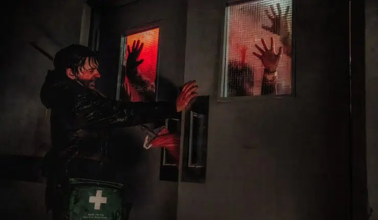 A man in a dark room holds back many trying to enter the room he's in.