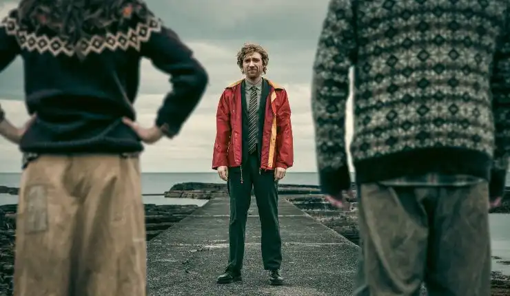 A man stands in front of a man and woman
